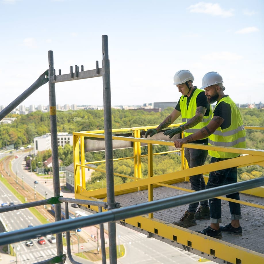 Mężczyźni stojący na zamontowanym na placu budowy podeście rozładunkowym TUP TLC Rental Strumin